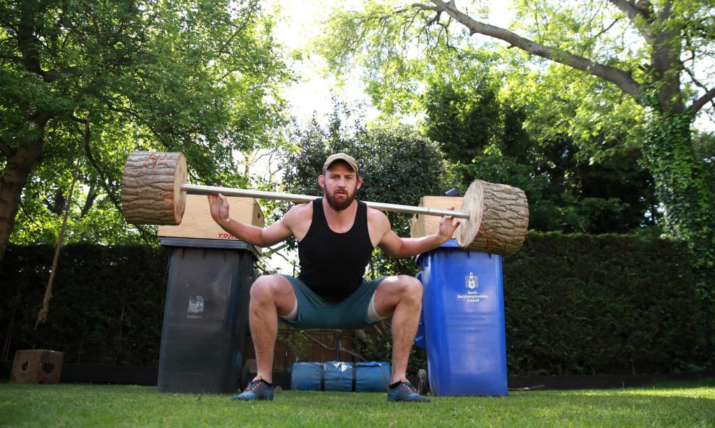 Tom Wood squats using a makeshift weight in his garden.