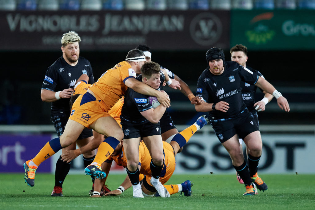 Huw Jones of Glasgow Warriors is tackled by Montpellier players